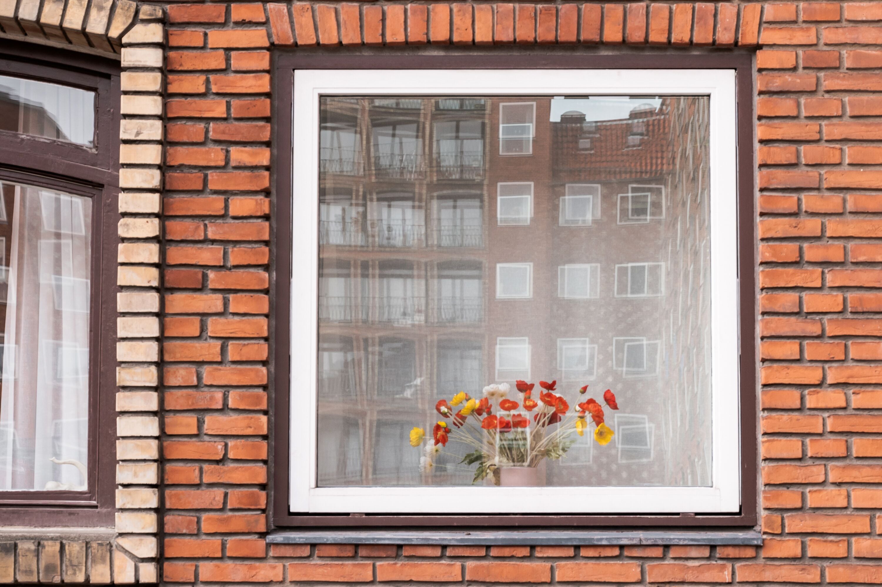 A window with a brick wall and a reflection of a building.