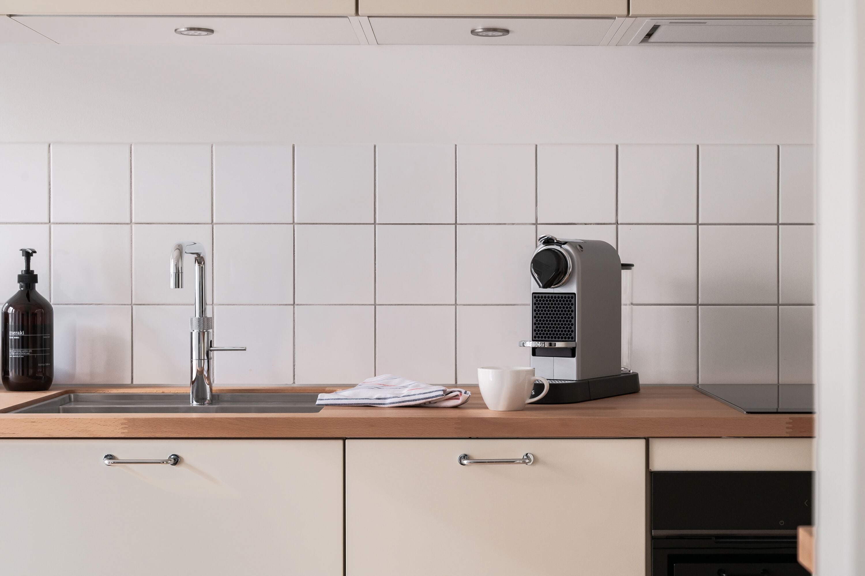 A modern kitchen with a stainless steel sink, a coffee machine, and a bottle of hand soap.