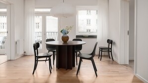 A dining area with a round table, black chairs, a vase with flowers, and a hanging light fixture. - Queens Courtyard (Copenhagen)