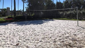 A sandy beach with a volleyball net, palm trees, and a building in the background. - 4 Bdr/3Bath Home - 3mi to Disney - Heated pool/spa - No rear neighbors! (Kissimmee)