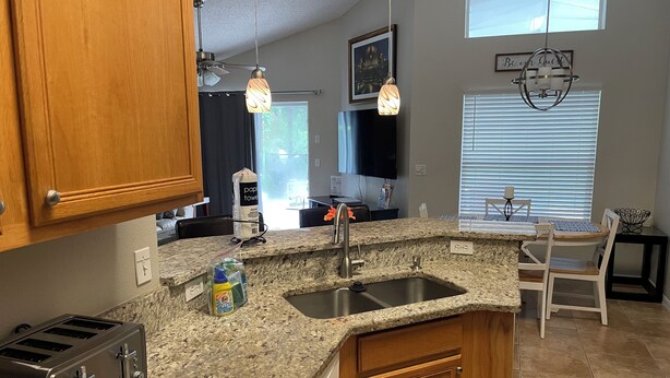A kitchen with granite countertops, wooden cabinets, a built-in toaster, and a window with blinds. - 4 Bdr/3Bath Home - 3mi to Disney - Heated pool/spa - No rear neighbors! (Kissimmee)
