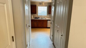 A narrow hallway leading to a kitchen with wooden cabinets and a window. - Cozy 2BR Near Atlanta|Sleeps 5|Free Parking (Lithonia)