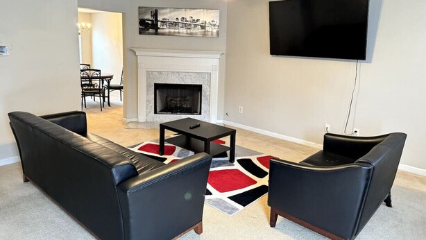 A living room with a fireplace, a ceiling fan, and a flat-screen TV mounted on the wall. - Cozy 2BR Near Atlanta|Sleeps 5|Free Parking (Lithonia)