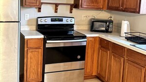 A kitchen with wooden cabinets, a stainless steel refrigerator, a black stove, a microwave, and a sink. - Cozy 2BR Near Atlanta|Sleeps 5|Free Parking (Lithonia)