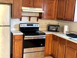 A kitchen with wooden cabinets, a stainless steel refrigerator, a black stove, a microwave, and a sink. - Cozy 2BR Near Atlanta|Sleeps 5|Free Parking (Lithonia)