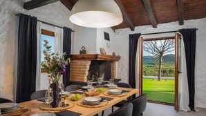 A dining area with a wooden table set for a meal, a fireplace, and a view of a green landscape. - Villa Olivella with Heated Pool (Vodice)