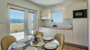 Enjoy a meal for two in this kitchen with a dining area, oven, and microwave, overlooking a scenic sea view.
