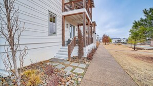 Une maison à deux étages dotée d’un balcon en bois et d’un chemin de pierre menant à la porte d’entrée.