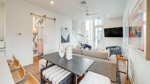 Un salon moderne avec un coin repas, un escalier et une grande fenêtre.