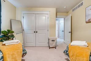 Two comfortable beds with yellow headboards, a potted plant, and a painting adorn this well-maintained room.