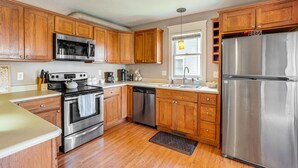 A kitchen with wooden cabinets, stainless steel appliances, and a window with blinds. - Charming Kalamazoo Home w/ Yard: 1 Mi to Downtown! (Kalamazoo)