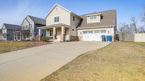 A two-story house with a front porch, garage, and a well-maintained lawn. - Charming Kalamazoo Home w/ Yard: 1 Mi to Downtown! (Kalamazoo)