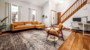 A living room with a sofa, a round coffee table, and a chair. There is a staircase leading to another level. - Family-Friendly 2BR Condo w/ Private Garage - Minutes from Zoo & Downtown (Fort Wayne)