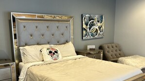 A bedroom with a large bed, a nightstand, a chair, and a wall-mounted artwork. - Spacious 6-bedroom house on Lake LB J (Granite Shoals)