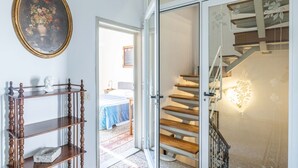 Eine Treppe mit Holzhinweisstufen und einer Glastür, die in ein Schlafzimmer mit Bett und Nachttisch führt.