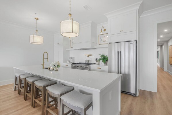 A modern kitchen with a large island, stainless steel appliances, and pendant lighting.