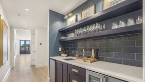 A modern kitchen with dark cabinetry, a white countertop, and a backsplash of dark tiles. - Luxury Condo Overlooking Downtown Fairhope #301 (Fairhope)
