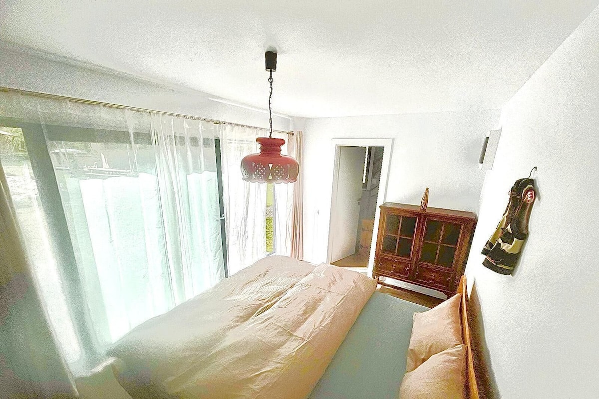 A bedroom with a large bed, a wooden cabinet, and a hanging shoe rack.