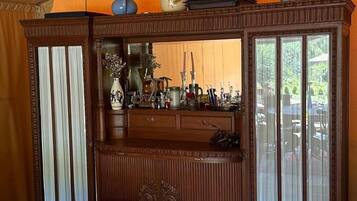 Un aparador tradicional de madera con puertas de cristal, un sillón estampado y una mesita con un jarrón de flores.