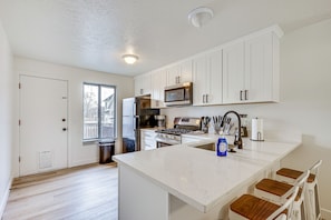 A modern kitchen with white cabinetry, stainless steel appliances, and a large island. - Near 4 Major Ski Resorts: Salt Lake County Home (Midvale)