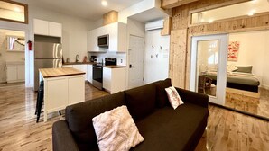 A modern living room with a sofa, a small table, and a kitchen area in the background. - The Flamingo ~ Cozy appartement in Saint-Roch - Downtown Quebec (Québec)