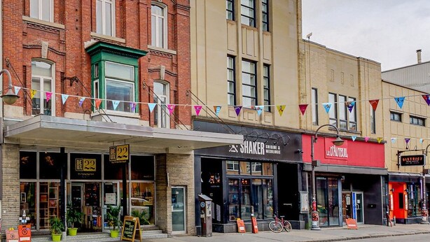 A row of brick buildings with storefronts, including a restaurant named 'Shaker.' - L'Ananas ~ A Charming Home in the Heart of Downtown (Québec)