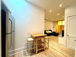 A compact living space with a kitchenette, a dining table, a sofa, and a television. - L'Ananas ~ A Charming Home in the Heart of Downtown (Québec)