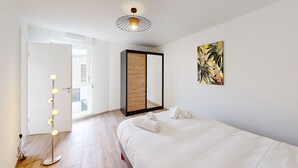 A hotel room with a bed, a mirror, a light fixture, and a painting.
