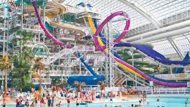Een groot overdekt waterpark met glijbanen en zwembaden.