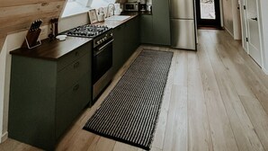 A modern kitchen with wooden walls, a gas stove, a refrigerator, and a window overlooking a deck. - Fox Ridge-Black Alder Lodging (Logan)