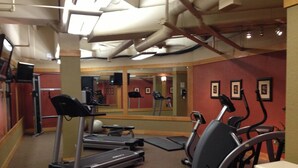 Une salle de sport équipée de tapis de course, de vélos elliptiques et de ballons d’exercice.