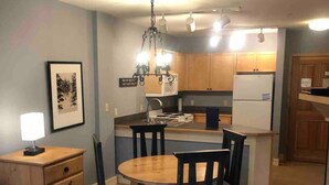 Un espace de vie compact comprenant un coin repas, une kitchenette et un petit coin salon.