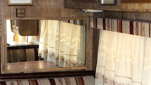Un intérieur de camping-car compact avec une table en bois, des sièges rembourrés à rayures et un mur miroir.