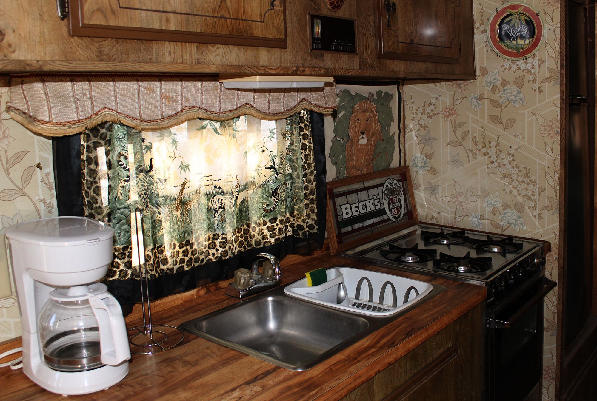 A kitchen with wooden cabinets, a stainless steel sink, a coffee maker, and a stove.