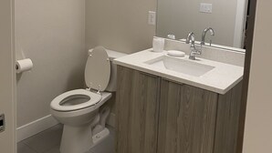 A bathroom with a toilet, sink, mirror, and wooden cabinets. - Private Quaint Cozy Room (Denver)