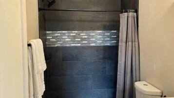 Un baño con ducha, inodoro y lavabo.