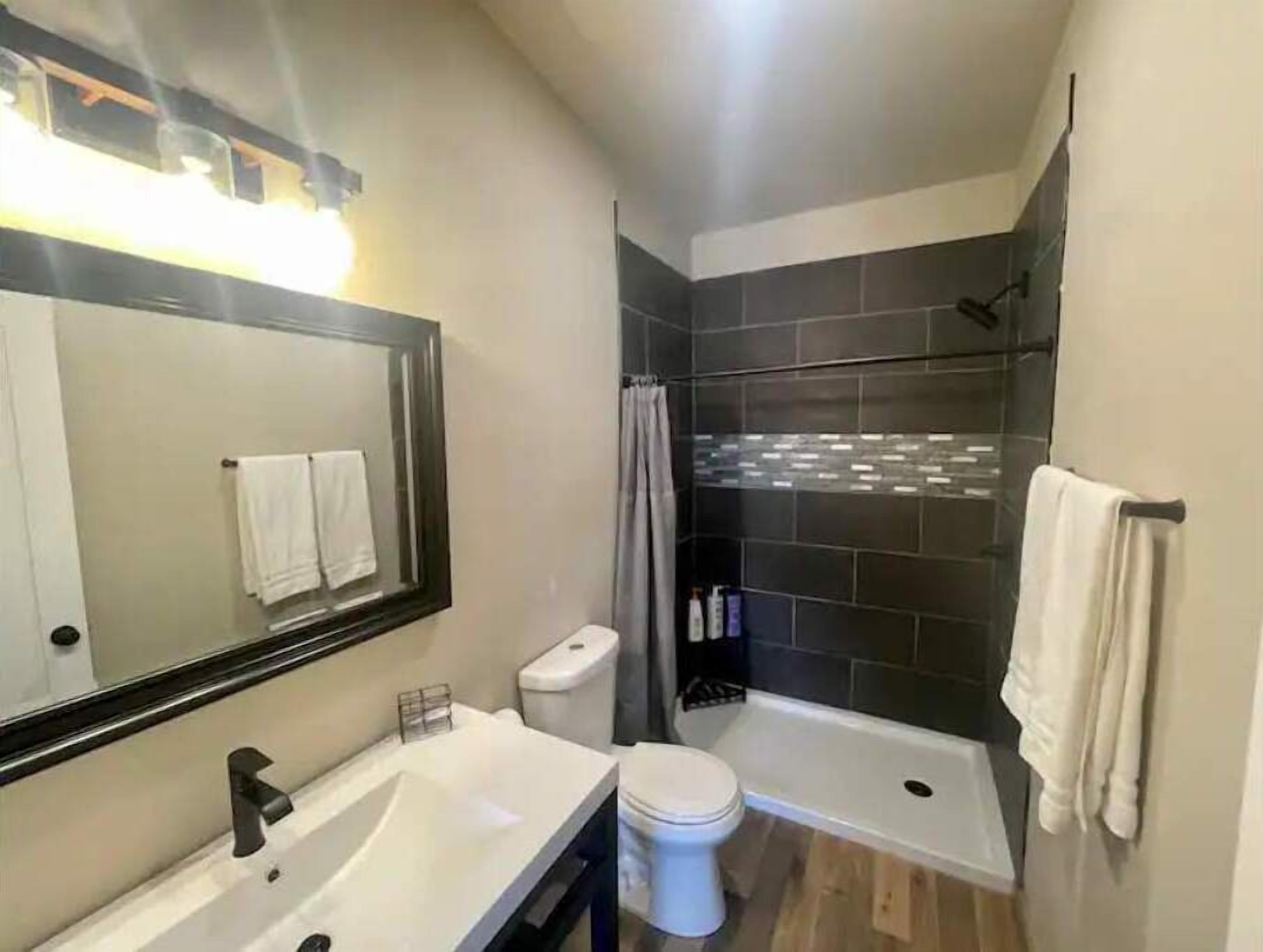 Une salle de bain moderne équipée d’un lavabo, de toilettes et d’une douche.