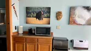A kitchen with wooden cabinets, a microwave, a refrigerator, and a coffee maker.