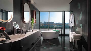 Un baño moderno con una bañera grande, lavamanos dobles y un amplio ventanal con vistas a la ciudad.