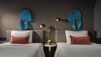 A hotel room with two beds, a small round table, and a wall-mounted lamp.