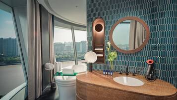 A modern bathroom with a large mirror, two sinks, and a view of the city.