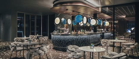 Un espace bar moderne avec un barman, des tables rondes et un design de plafond original.