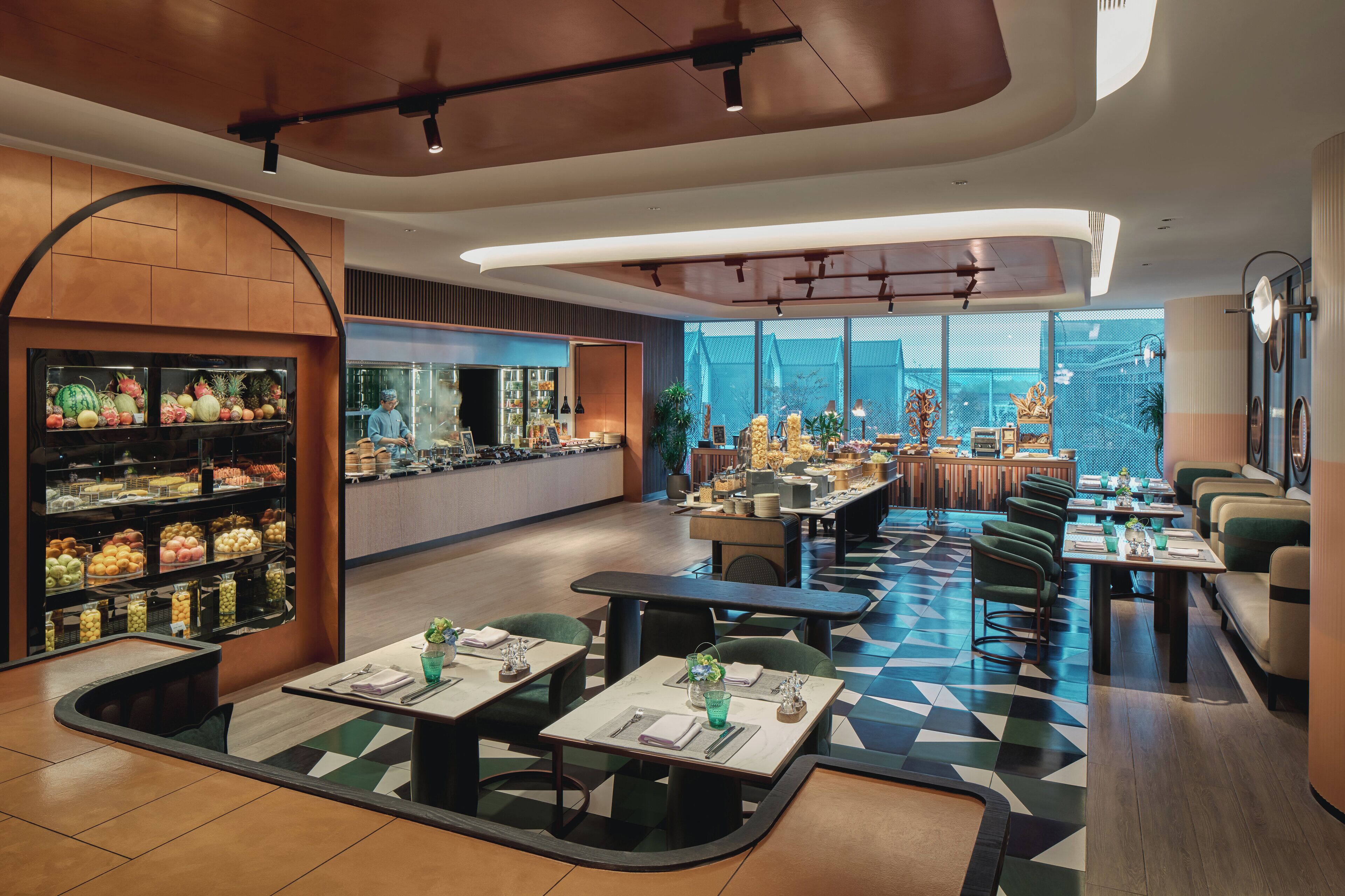 A modern restaurant with a checkered floor, a fruit display, and a view of the city.