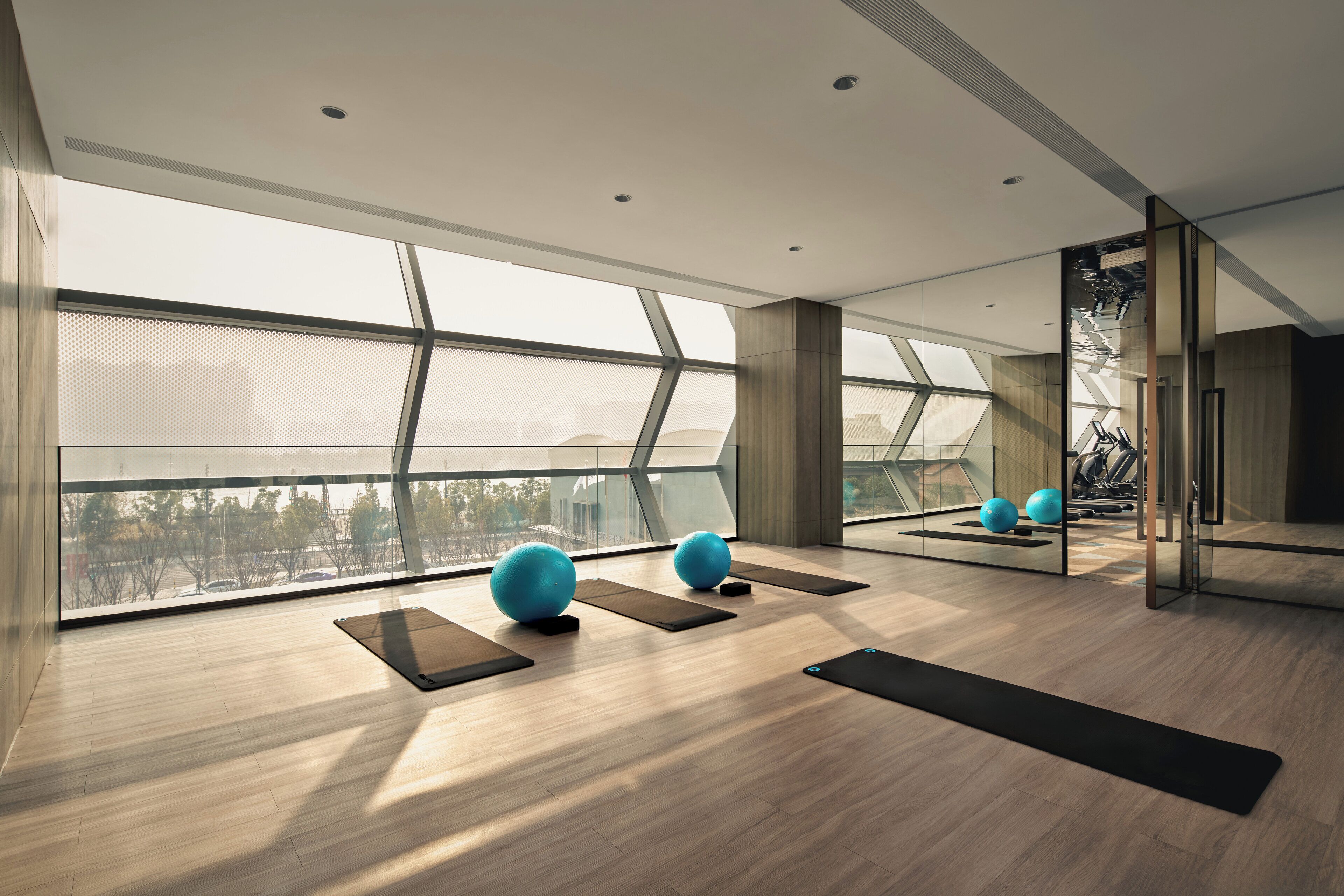 Un gimnasio moderno con equipo de ejercicio, ventanas amplias y vistas a la ciudad.
