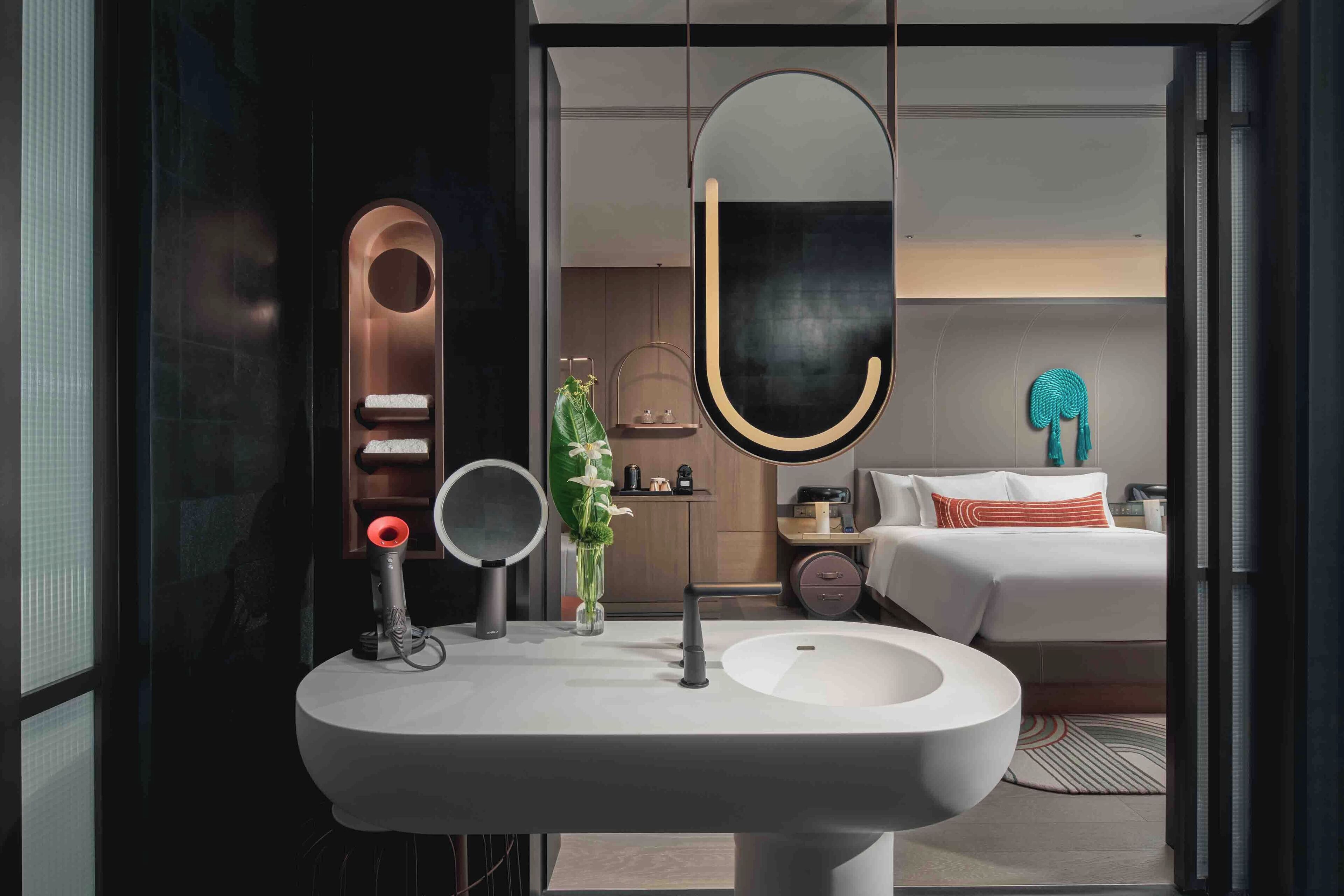 A modern bathroom with a large mirror, a round sink, and a towel rack.
