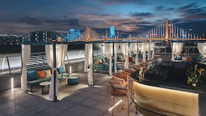 A rooftop bar with a city skyline view, outdoor seating with umbrellas, and a bar counter. - Hotel Indigo Ningbo Riverside by IHG (Ningbo)