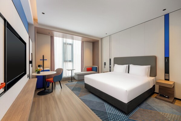 A modern hotel room with a large bed, a desk with a chair, a small table, and a TV. - Holiday Inn Express Liaocheng Etdz by IHG (Liaocheng)