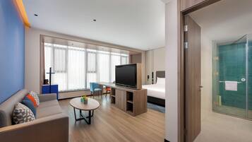 Habitación de hotel con cama, televisión, zona de estar y baño.
