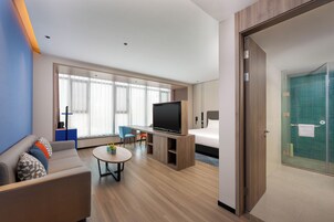 Habitación de hotel con cama, televisión, zona de estar y baño.