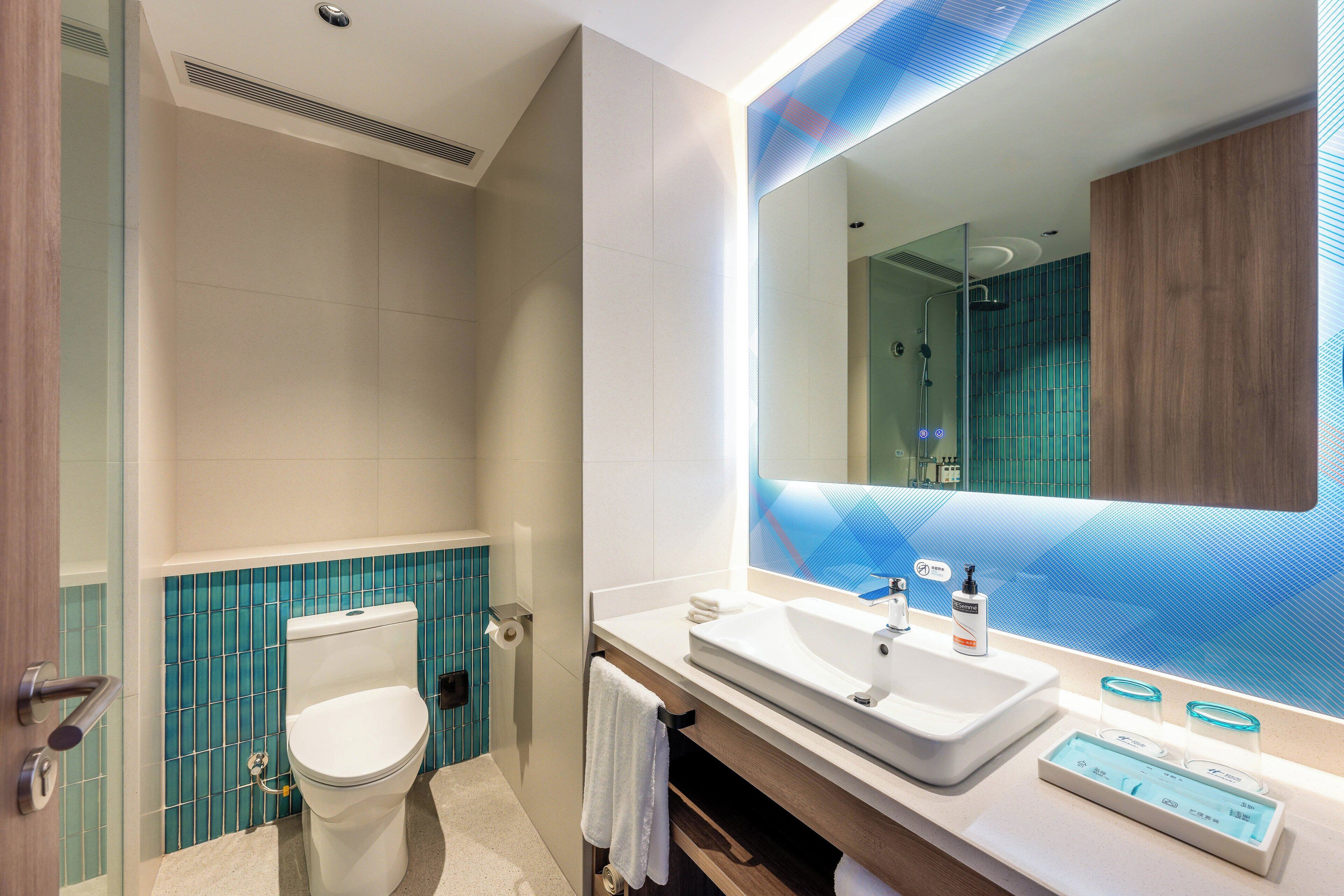 A modern bathroom with a toilet, sink, and large mirror.